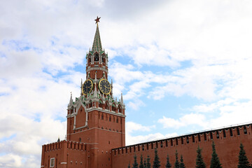 Obraz premium Red square in Moscow with Kremlin tower, chimes and brick wall on background of blue sky with clouds. Symbol of Russian authorities
