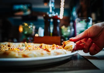 Foto op Canvas woman Hand takes a slice of meat Pizza with Mozzarella cheese, salami, Tomatoes, pepper, ham in cafe © pavel siamionov