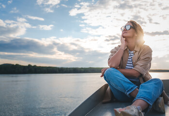 Young adult caucasian happy woman relaxing on a boat on the river enjoying a boat trip
