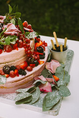 Große zweistöckige Hochzeitstorte mit Beerencreme und frischen Beeren, dekoriert mit Himbeerkuchengrün-Hochzeitszeremonie