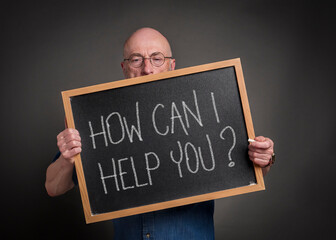 How can I help you? Senior man, teacher, mentor or presenter with a blackboard sign, education,...