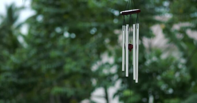 Wind Chimes hangs on the porch of the house against the backdrop of green trees