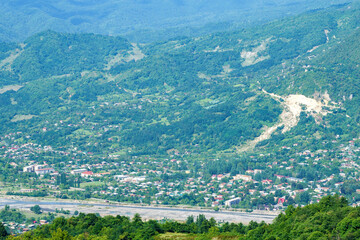 Fototapeta na wymiar Georgian mountain landscape with a country road, a view of the village on the banks of a mountain river