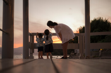海で綺麗な夕日を眺めている親子