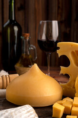 Varied cheese table, blue cheese Fontina Gruyer Cheese Teetilla in wooden table with red wine glass Pimentero oil and Round homemade fields of field and rustic knife