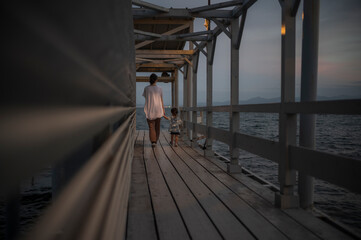 夕焼けの桟橋を歩く親子