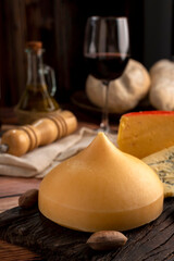 Varied cheese table, blue cheese Fontina Gruyer Cheese Teetilla in wooden table with red wine glass Pimentero oil and Round homemade fields of field and rustic knife
