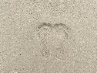 Woman footprint stamp on sand ground at the beach. Rough surface texture in nature.