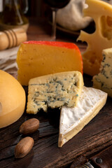 Varied cheese table, blue cheese Fontina Gruyer Cheese Teetilla in wooden table with red wine glass Pimentero oil and Round homemade fields of field and rustic knife