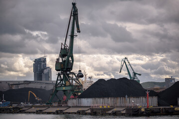 MARITIME TRANSPORT - Port crane on the quay with coal on the reloading yard