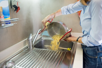 Close up senior woman draining cooked pasta