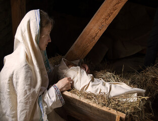 Woman near the baby in the manger - obrazy, fototapety, plakaty