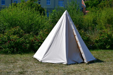 A close up on a tent made out white cloth with a wooden frame and ropes supporting it seen during a...