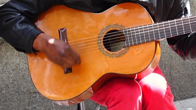 The musician plays the guitar and sings on the Street.