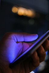 Close up of man's hand using smart phone at night 