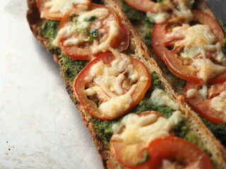 toasted baguette with pesto spread, sliced fresh tomato and mozzarella cheese