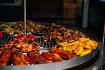 Grilled vegetables and meat. Food market: Large metal grill for frying.  Tomatoes, potatoes, pepper, zucchini, steak, chicken, mushrooms