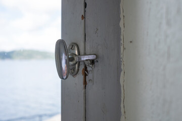 Metal latch on the frame of an old white painted wooden window. Close-up.
