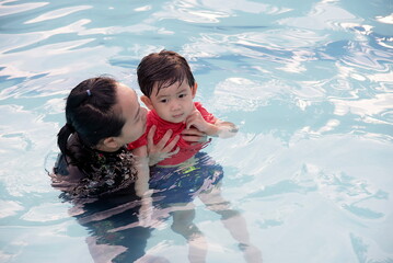 Mother teach her son to swim in swimming pool