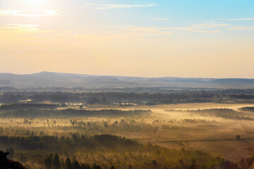 Foggy dawn over the valley. Autumn landscape at sunrise with low fog. Morning mist haze over trees