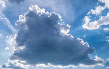 Obraz premium The sun is behind the cloud. Summer sky. Clouds illuminated by the sun from behind.