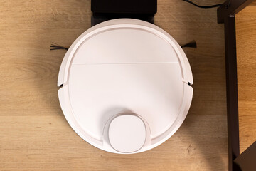 Modern white robot vacuum cleaner based on wooden floor