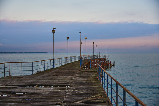 A pier stretching far out to sea against the sunset.