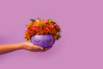 Purple pumpkin decorated with flowers in hand. Halloween Concept