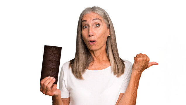 gray hair pretty woman looking astonished in disbelief with a chocolate bar