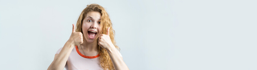 Happy young caucasian redhead female in summer shirt holds her head. Concerned girl looks cautiously to the side, feeling pressured and perplexed.