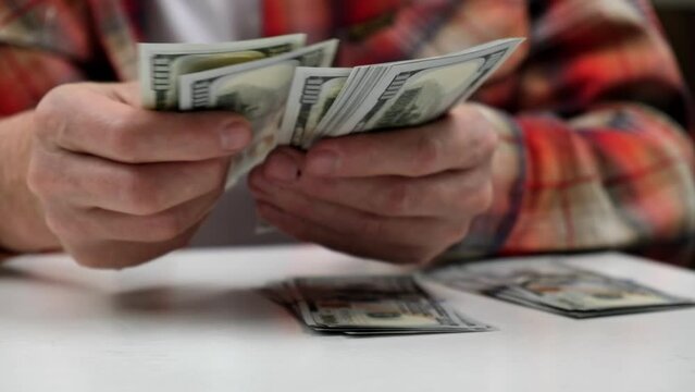 budget allocation of money. the man counts cash hundred-dollar bills of the USA and puts them in stacks. employee's salary. close-up of men's hands counting money. finance and investments.