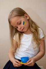 little Ukrainian woman with a picture of the flag of Ukraine and the heart of peace