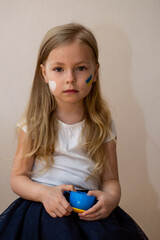 little Ukrainian woman with a picture of the flag of Ukraine and the heart of peace