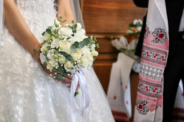 The bride holds a beautiful bouquet of flowers in her hands during the wedding.