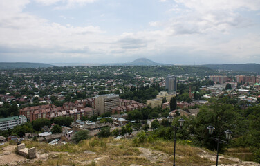 Panoramic top view of Pyatigorsk, Stavropol territory with residential buildings among green trees and cloudy sky above the horizon