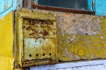 an old mailbox at the entrance to the house, weathered paint on the walls