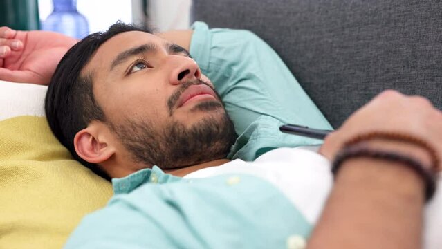 Heartbreak, depression and sad man with phone on sofa thinking, feeling and mourning for crying, emotional anxiety and mental healthy stress. Depressed, unhappy and lonely guy waiting for mobile text