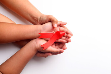 Woman's hand and child's hand holding red ribbon together over white with copyspace. Aids day concept - obrazy, fototapety, plakaty