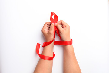 Close up photo of woman's hand holding red ribbon over white background with copyspace. Aids day concept