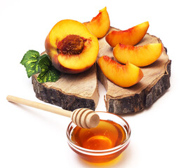 Peach slices on a wooden board and honey with a wooden spoon. Shallow depth of field