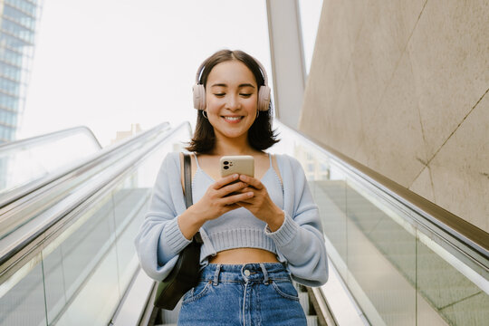 Young Beautiful Asian Smiling Happy Girl In Headphones With Phone