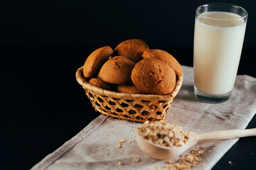 Oatmeal cookies with a glass of milk on a napkin on a black background. The concept of a healthy breakfast