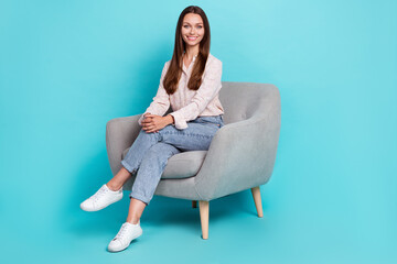 Fototapeta na wymiar Full length photo of pretty positive lady stylish clothes outfit sit enjoy chair legs crossed empty space isolated on cyan color background