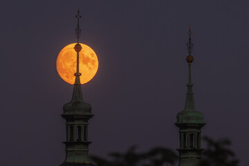 Fototapeta na wymiar super full moon just after rising , behind the church tower the thirteenth of July 2022