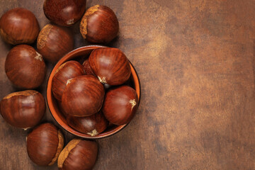 Chestnuts in a bowl  on a wooden background. Autumn fall seasonal composition with horse chestnuts....