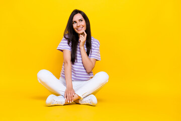 Photo of pretty sweet minded lady sit floor arm touch face interested look empty space cunning creative plan isolated on yellow background
