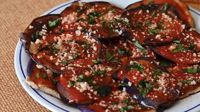 Close up of eggplant parmigiana, also eggplant parmigiana or simply parmigiana, is a dish made with fried eggplant au gratin with tomato sauce, basil, garlic and cheese.