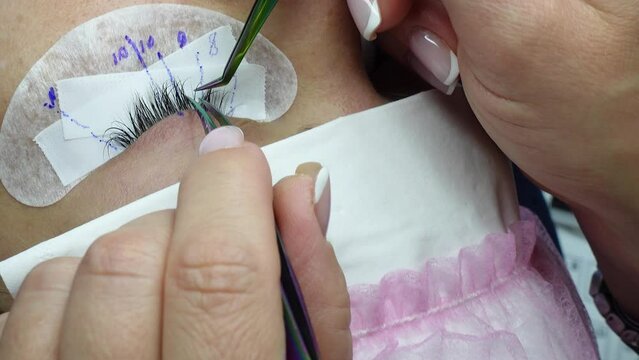 Eye lash extension procedure. Young beautiful woman eye with long false eyelashes. Close up macro shot of eyes in beauty salon. Beauty and fashion concept for Lash extensions master.