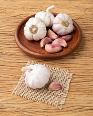 Garlic bulb and cloves on a plate over wooden table