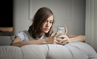 portrait of young woman sitting on an armchair while using a smartphone